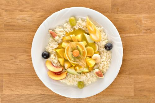 a white plate of oatmeal with fruit and nuts at Hotel Restaurant Möve in Faulensee
