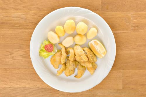 a plate of food with fish and chips and lemon slices at Hotel Restaurant Möve in Faulensee