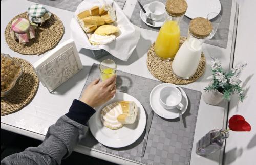 a person holding a glass of juice and a plate of food at My Hostel in Guimarães