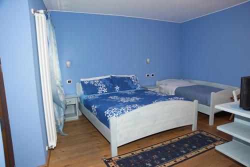 a bedroom with two beds and a blue wall at B&B La Maison D' Amelie Camere e Appartamenti in Fenis