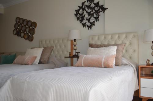 a bedroom with two beds with white sheets and pink pillows at Recoleta Deluxe Studio in Buenos Aires