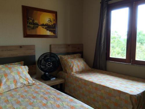- une chambre avec 2 lits et une fenêtre dans l'établissement Guaramiranga Apart Monte Verde, à Guaramiranga