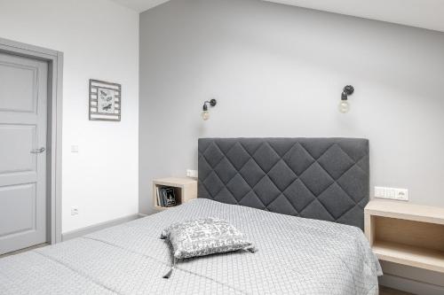 a white bedroom with a bed with a gray headboard at Comfort Stay - Klaipeda in Klaipėda