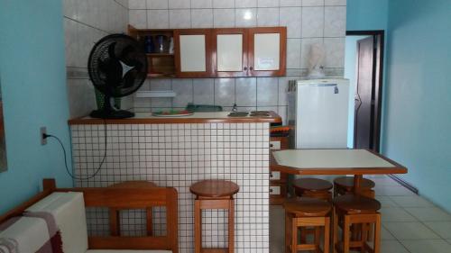 cocina con mesa, sillas y nevera en Sobrado Hibisco en Capão da Canoa