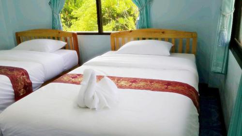 Golden Palm Resort في شيانغ ماي: غرفة بسريرين عليها طير ابيض