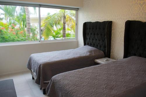 a bedroom with two beds and a window with palm trees at Condominio de Lujo con Playa y Alberca in Mazatlán