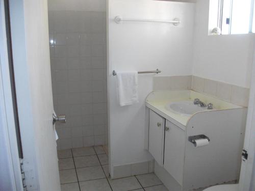 uma casa de banho branca com um lavatório e um chuveiro em Beerwah Glasshouse Motel em Beerwah
