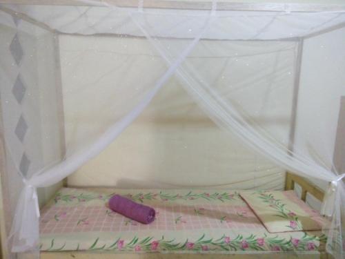 a small bed with a canopy and a pillow at Novita Homestay in Bunaken