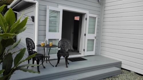 un patio con 2 sillas y una mesa en un porche en Villa on Milton en Nelson