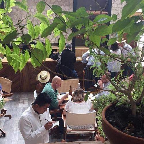 a group of people sitting at tables in a restaurant at Casa Tsaya Hotel Boutique in Bernal