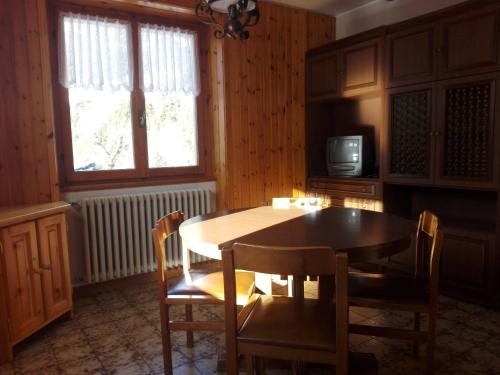 una sala da pranzo con tavolo, sedie e TV di Chalet Bianco a Valdidentro