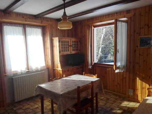 a dining room with a table and two windows at Chalet Bianco in Valdidentro