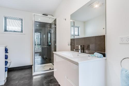 a white bathroom with a sink and a mirror at Apartments on Fraser Bicheno in Bicheno