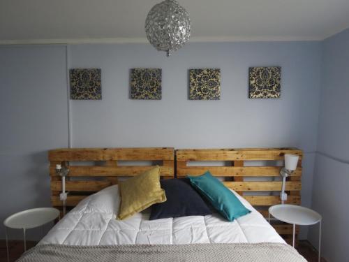 a bedroom with a wooden bed with four pictures on the wall at Mi Paz in Valparaíso