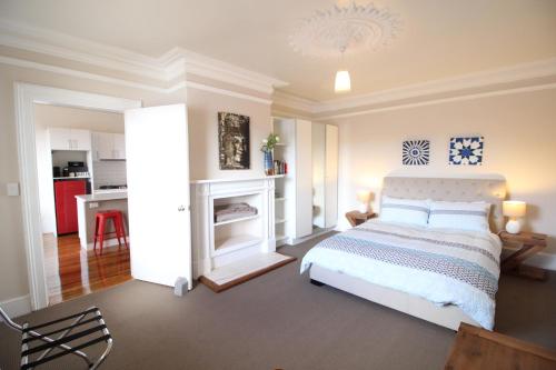 Un dormitorio con una cama blanca y una cocina. en Trinity Hill Apartments, en Hobart