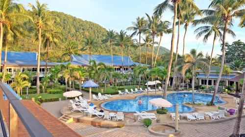 a resort with a pool and chairs and palm trees at Andaman Lanta Resort - SHA Extra Plus in Ko Lanta