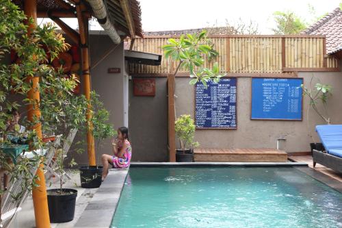 
a woman sitting in a pool next to a swimming pool at The Lakshmi Villas in Gili Trawangan
