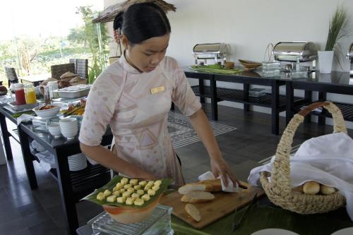 een vrouw in een keuken die eten bereidt op een snijplank bij Mekong Riverside Boutique Resort & Spa in Cai Be