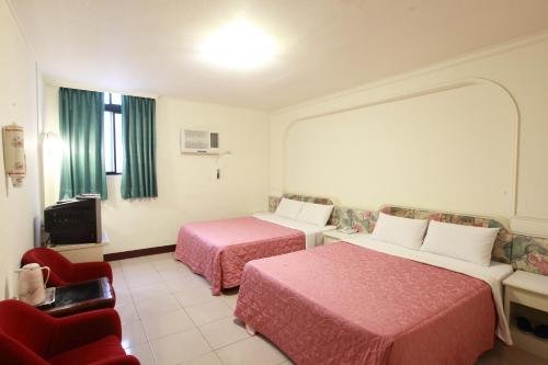 a hotel room with two beds and a chair at Yong Qi Hotel in Hualien City
