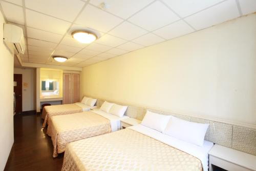 a room with three beds in a room at Yong Qi Hotel in Hualien City