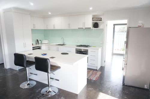 a kitchen with a white counter and two chairs at Ben's Place - modern & convenient in Mansfield