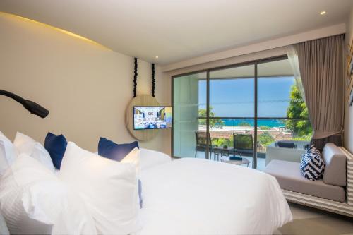 a bedroom with a white bed and a large window at The SIS Kata, Resort - SHA Plus in Kata Beach