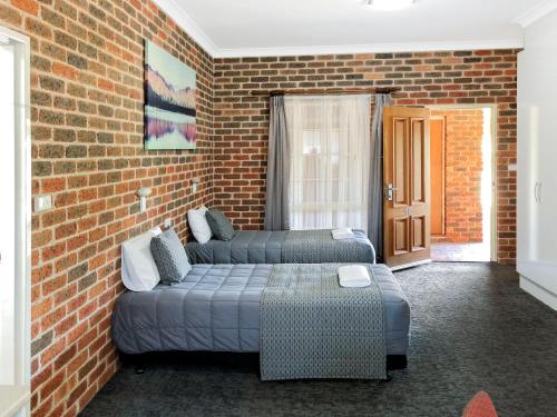 ein Wohnzimmer mit einer Couch und einer Ziegelwand in der Unterkunft Leeton Heritage Motor Inn in Leeton