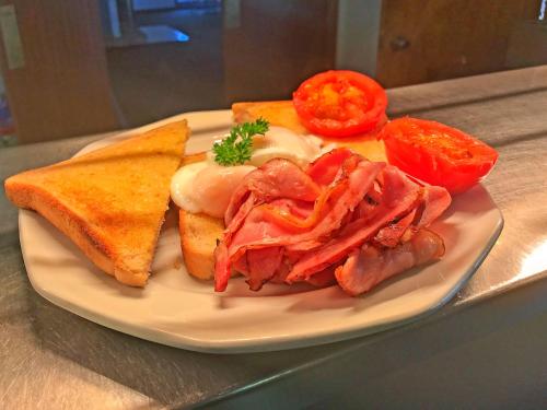 une assiette de nourriture avec de la viande, du pain et des tomates dans l'établissement Leeton Heritage Motor Inn, à Leeton