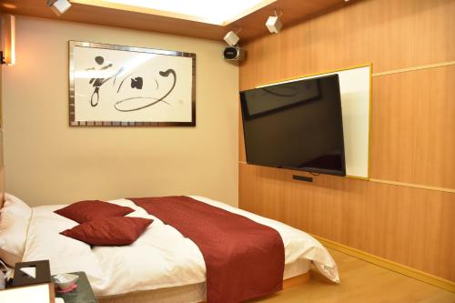 大分的住宿－可可棕櫚＆梅爾情趣酒店，一间卧室配有一张床和一台平面电视