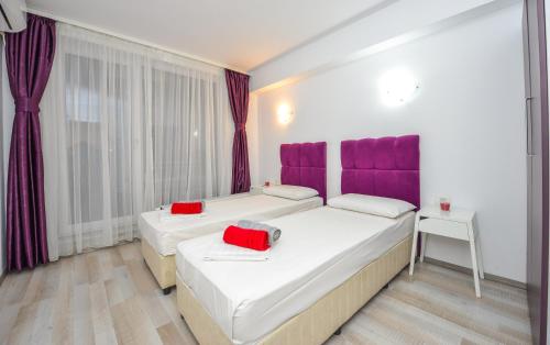 two beds in a room with purple accents at Harmony Suites in Bucharest