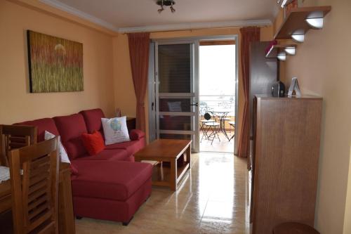 a living room with a red couch and a table at Apartamento Nek in San Sebastián de la Gomera
