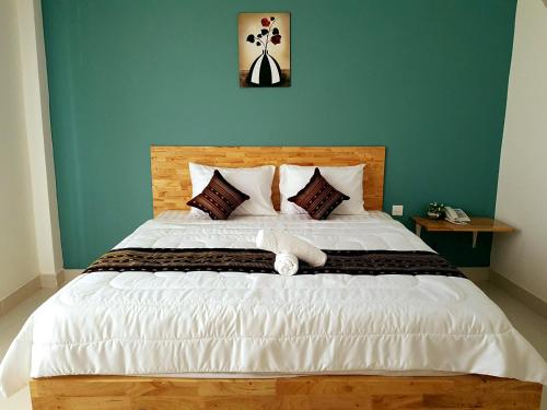1 dormitorio con 1 cama blanca grande y pared azul en Lucky Hostel, en Battambang