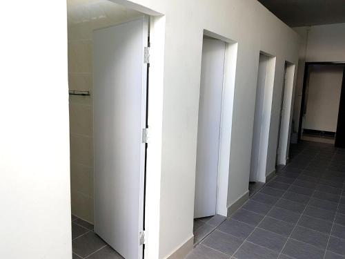 a hallway with white doors and a tile floor at Lucky Hostel in Battambang