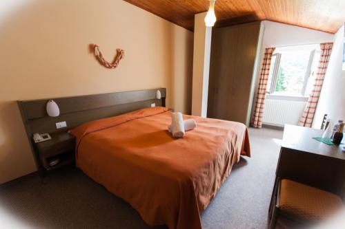 a bedroom with a bed with a teddy bear on it at Garden Hotel Bellariva in Molveno