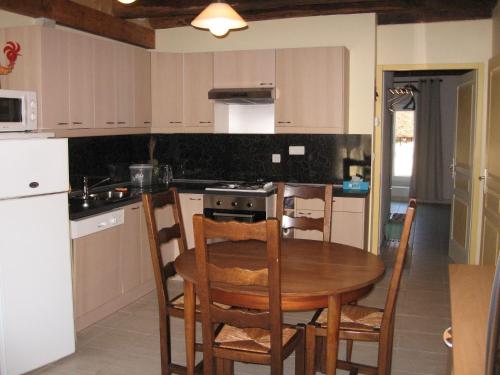 a kitchen with a wooden table and a table and chairs at Chez Robert et Catherine in Dompierre-sur-Mont