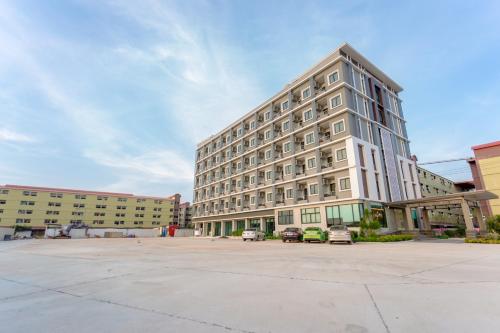 a large building with cars parked in a parking lot at Grand Inter Hotel in Samut Sakhon
