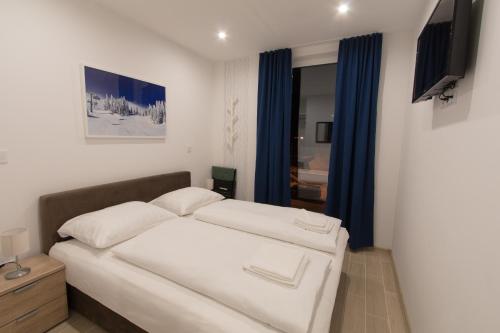 1 dormitorio con cama blanca y cortinas azules en Apartmani MONT 1, en Jahorina