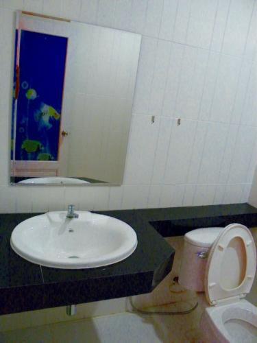 a bathroom with a sink and a toilet and a mirror at Wangthong Beach Resort in Laem Sing