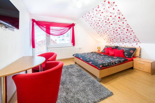 - une chambre avec un lit, une table et des chaises rouges dans l'établissement Apartmánový dom Adriana, à Zuberec