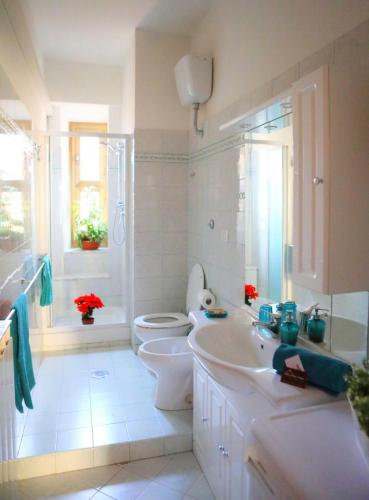 a white bathroom with a toilet and a sink at Linda Musei Vaticani in Rome