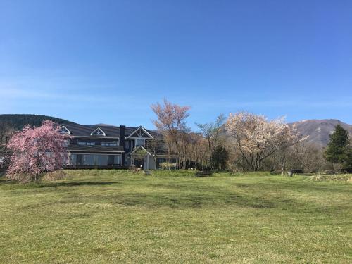 a large black house on a grassy field at 久住高原 赤川温泉スパージュ-Spaju in Taketa