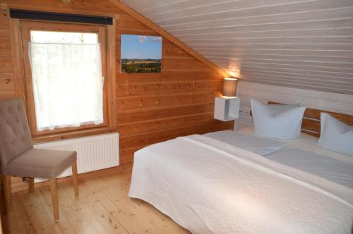 a bedroom with a bed and a chair and a window at EIFELCOTTAGE Family 9 in Ulmen