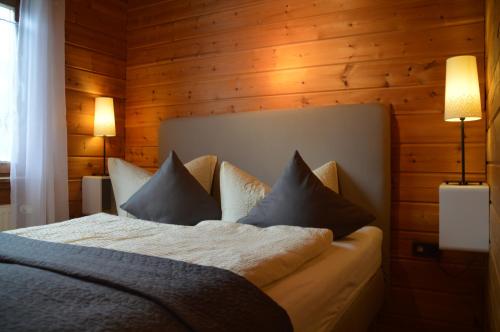 a bedroom with a bed with wooden walls and two lamps at EIFELCOTTAGE Family 9 in Ulmen