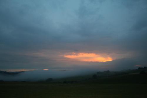 a foggy field with a sunset in the background at EIFELCOTTAGE Family 9 in Ulmen