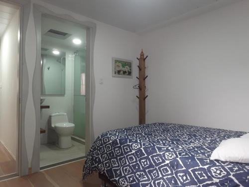 a bedroom with a bed and a bathroom with a toilet at Elizabetha Hostal in Salento