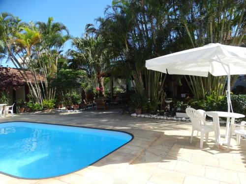 a pool with a table and an umbrella at Pousada Sonho de Geribá in Búzios