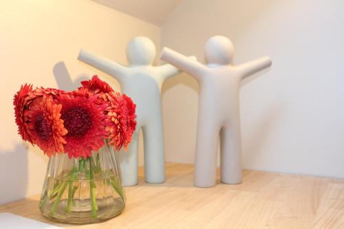 three white manicans standing next to a vase with red flowers at Mille Étoiles in Moorsel