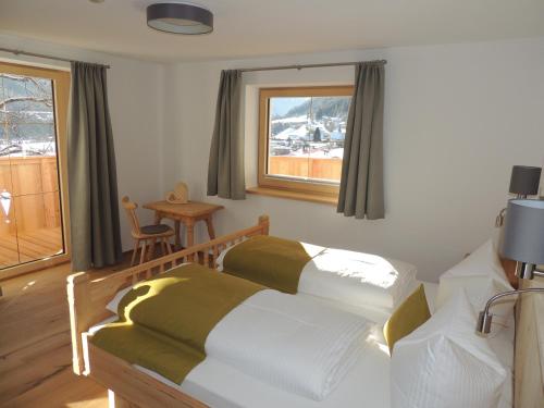 a bedroom with two beds and a table and a window at Buttererhof-Apartments in Fulpmes