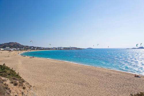 a beach with people flying kites in the water at Naxos Luxury Villas in Mikri Vigla