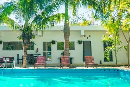 a pool with chairs and palm trees in front of a house at Hotel 41 Valladolid in Valladolid